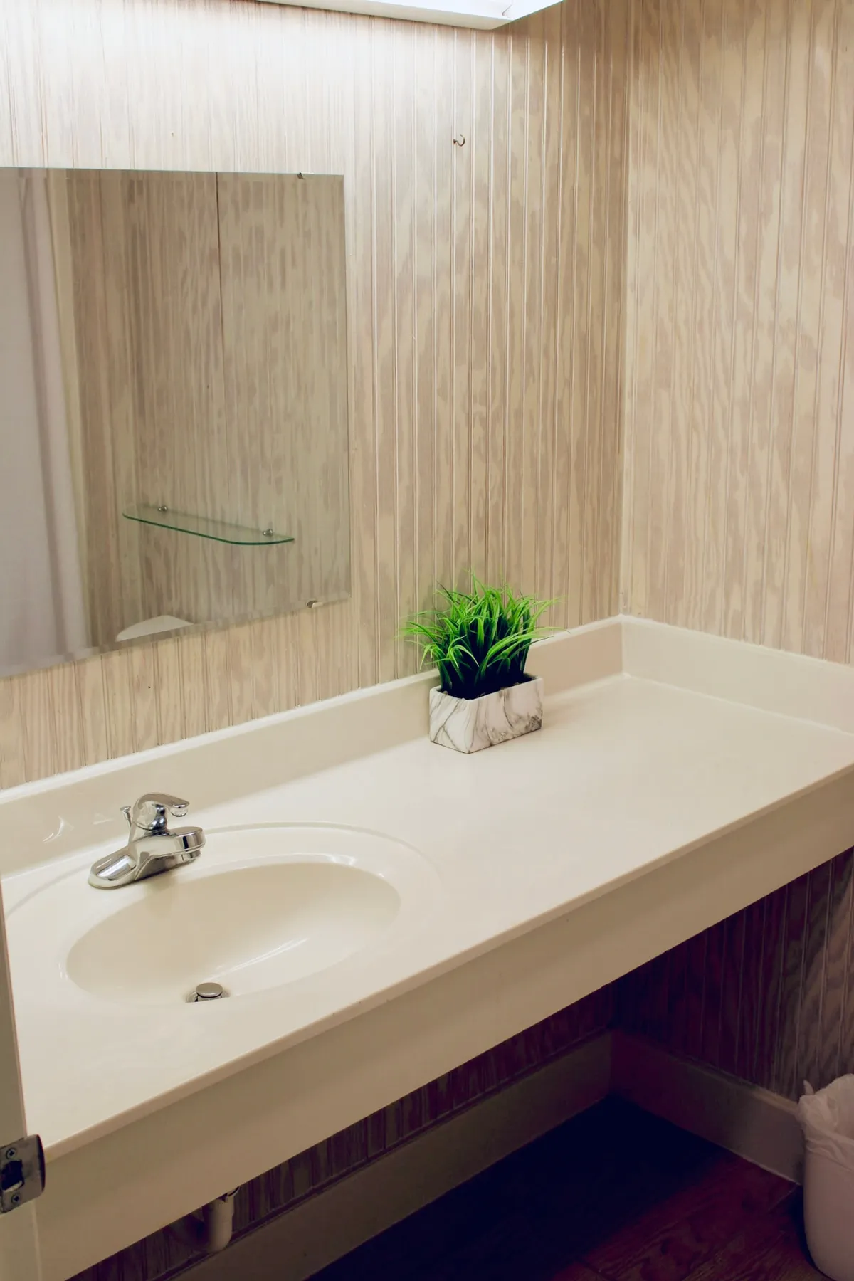 A fresh, inviting bathroom interior featuring a modern sink, a large mirror, and a touch of greenery from a potted plant. The space exudes cleanliness and comfort, ideal for grooming and relaxing after a long day.