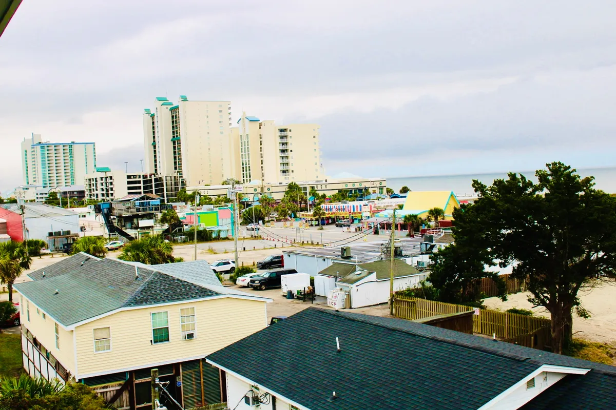 This lively scene captures tall buildings, a colorful boardwalk, and palm trees—a vibrant snapshot of the beachside atmosphere. The area is bustling with opportunities for shopping, dining, and amusement rides, hinting at the nearby attractions and activities.